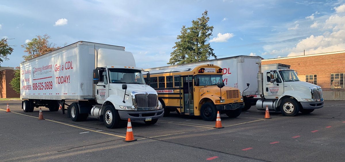 Two tractor-trailers and one school bus in practice yard
