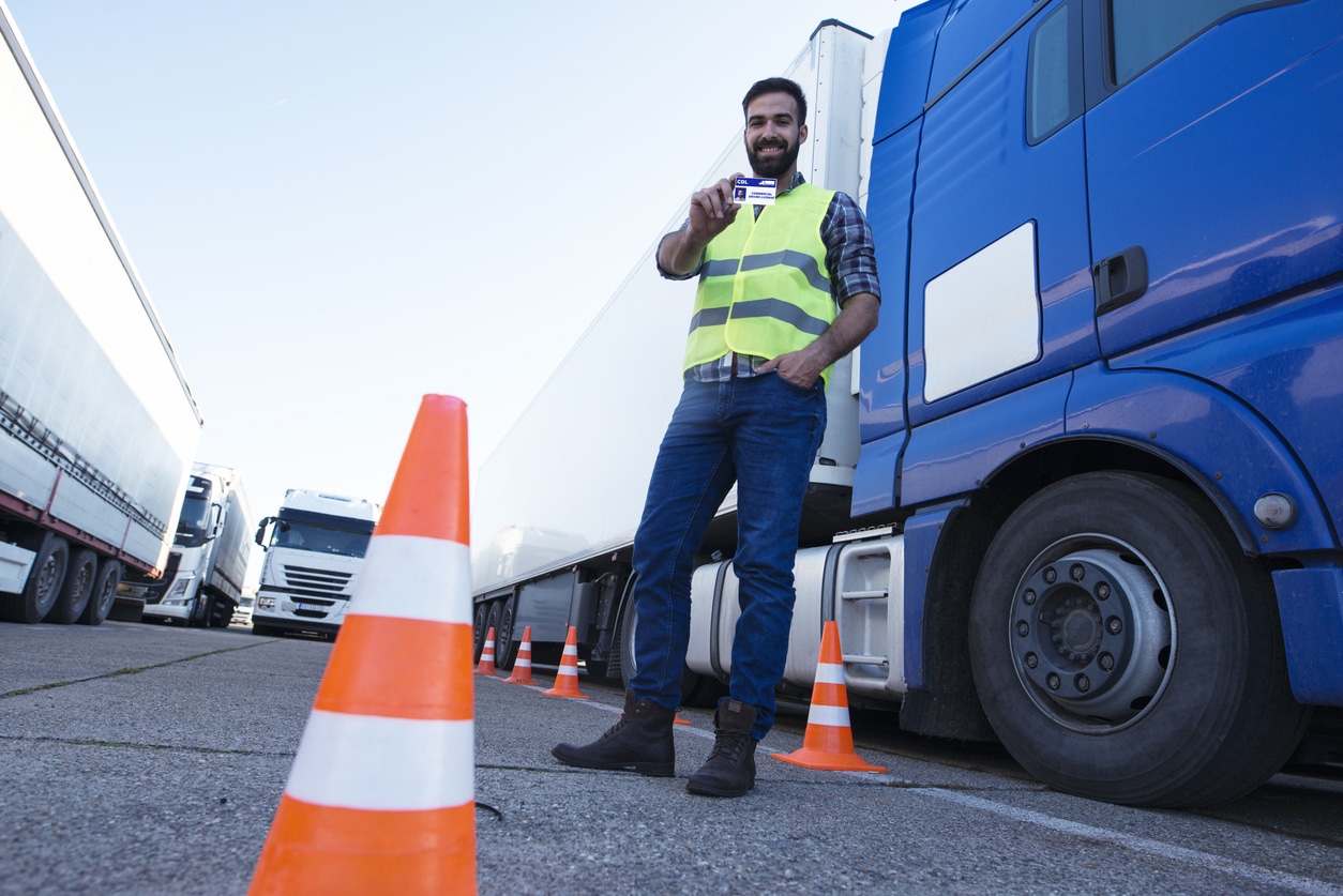Truck driver holding license in front of trucks
